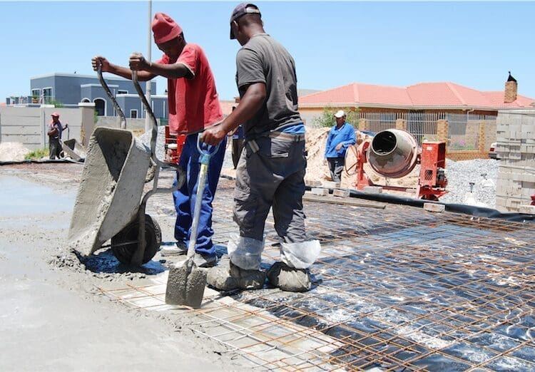Construction workers pour cement on site, reflecting the labour-intensive building industry where leaders and SMEs are calling for practical regulation that balances compliance requirements with worker protection.
Photo: SANS